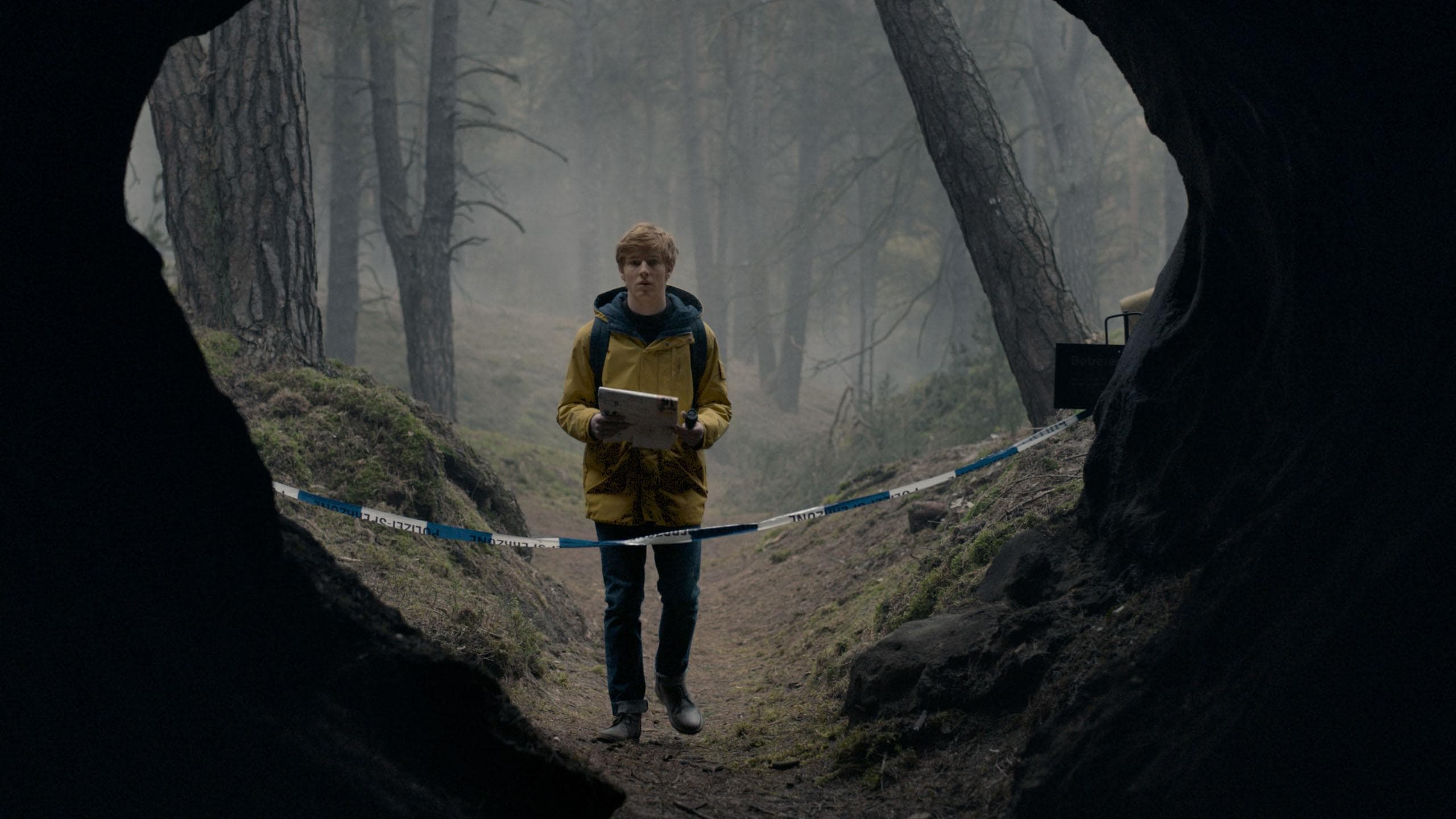 Jonas Kahnwald (Louis Hofmann) stands in the cave wearing the yellow jacket from “Dark“. <small>© Netflix</small>